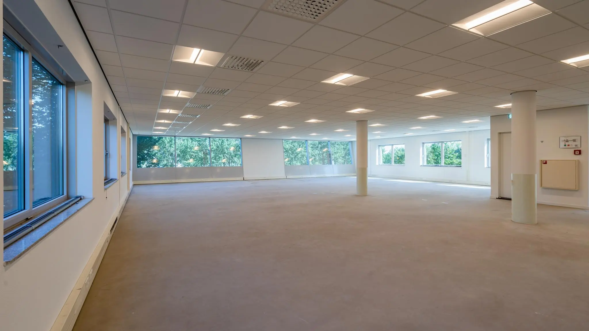 Leeg en licht kantoorruimte-interieur aan de Rivium Promenade met grote ramen en systeemplafond.